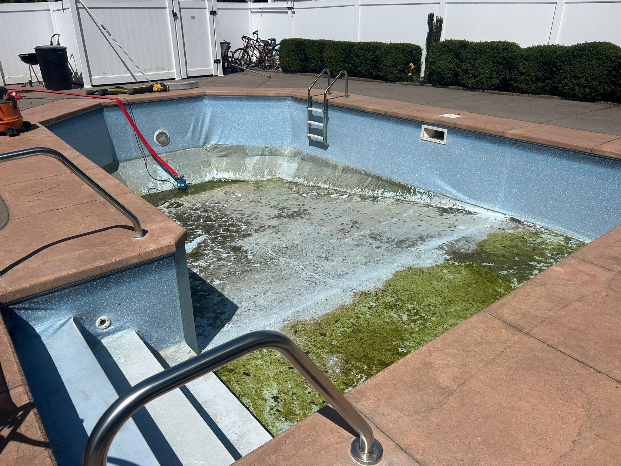 Drained pool with algae sludge and old liner