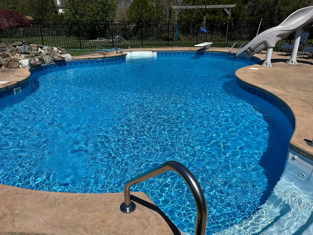 Crystal blue freeform pool with slide and rock waterfall after cleaning